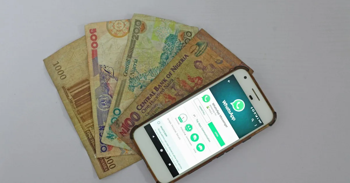 A smartphone lying beside a spread of banknotes on a table.